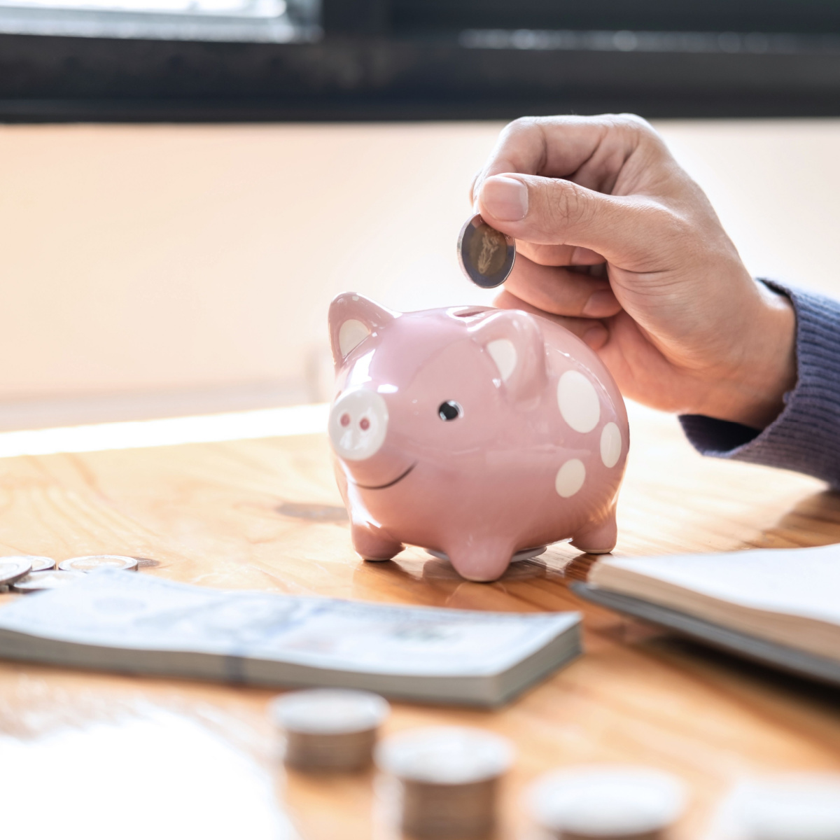 A man dropping a coin into a piggy bank to symbolize holistic planning for retirement backed by expert financial consulting